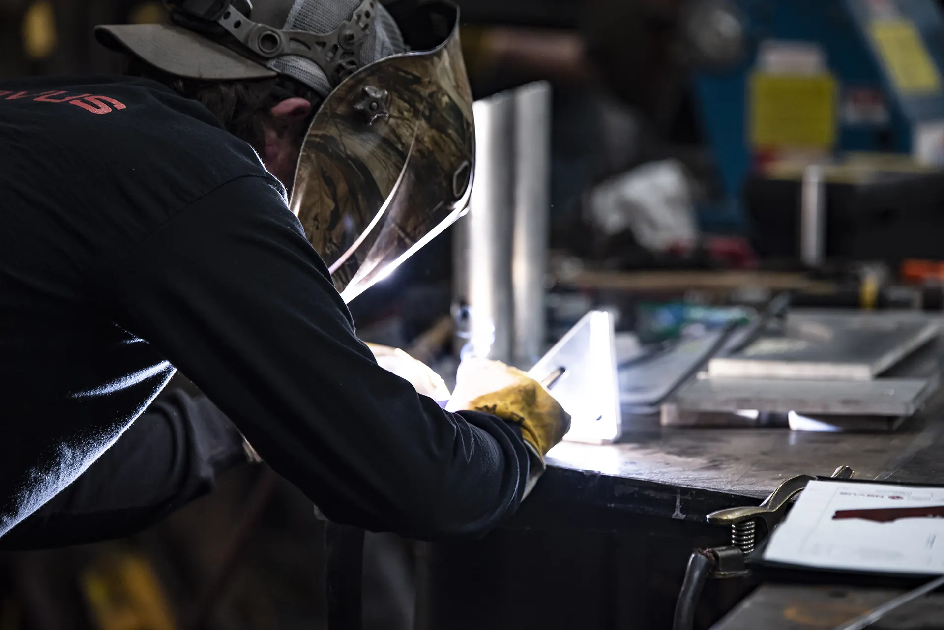 Welder working on metal at workshop.